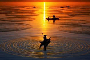 Men fishing on boats in the water at sunset