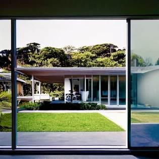 hyper realistic eye level exterior photo of a mid century modern style house overlooking the ocean, daylight, indirect lighting, AD magazine, Frank Lloyd, Eames, Mies van der Rohe