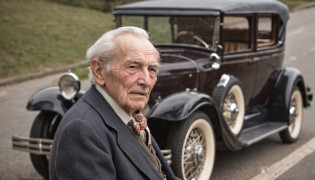 Nostalgic Elegance
Capture a confident OLD-aged MAN in the midst of the 1970s era. The fashion, furniture, and architecture should ooze the essence of that time. Enhance the scene with classic cars from the same period to complete the vintage look. Ensure intricate details in attire, surroundings, and automobiles.