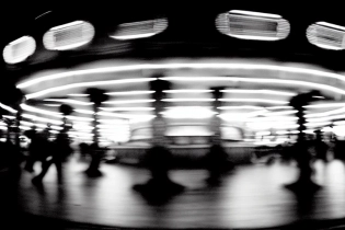distant photography of a merry go round | dark night | bright lights | rain | 35 mm | f/16 | film photo | studio ghibli | blurry | motion blur
