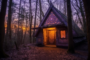 A mystical cabin nestled in an enchanted forest. The cabin is adorned with intricate carvings and glowing runes. Soft, ethereal light filters through the windows, casting magical patterns on the wooden floors. The surrounding trees are tall and ancient, their branches reaching out like guardians. The sky above is painted with vibrant hues of purple and gold, as if touched by the magic of the cabin itself. camera-focal-length 35mm, camera-aperture f/4, camera-shutter-speed 1/100 --aspect 3:2 --chaos 30 --stylize 600 --quality 1. 5 --s 50 --v 5. 1 --style raw