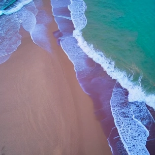 drone view of purple sea waves at the beach, sunset, dog walking leaving purple paw prints on the sand