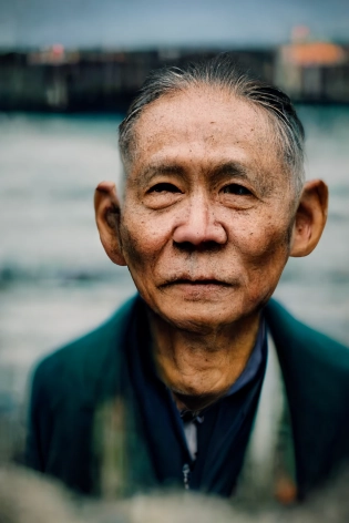 a photo portrait of a really old Taiwanese man posing for a picture near the docks --test --ar 2:3 --stop 88 --uplight