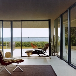 Hyper realistic eye level exterior photo of a mid century modern style house overlooking the ocean, daylight, indirect lighting, AD magazine, Frank Lloyd, Eames, Mies van der Rohe
